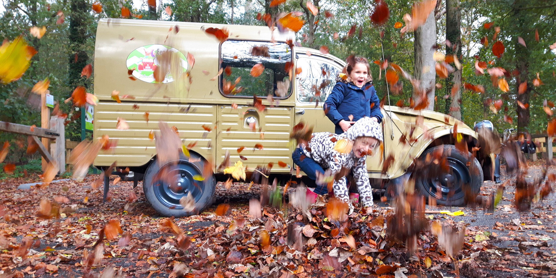 kinderen in het Staelduinse Bos in het Westland die aan het spelen zijn met dorre bladeren voor een 2CV van Eendentours Westland